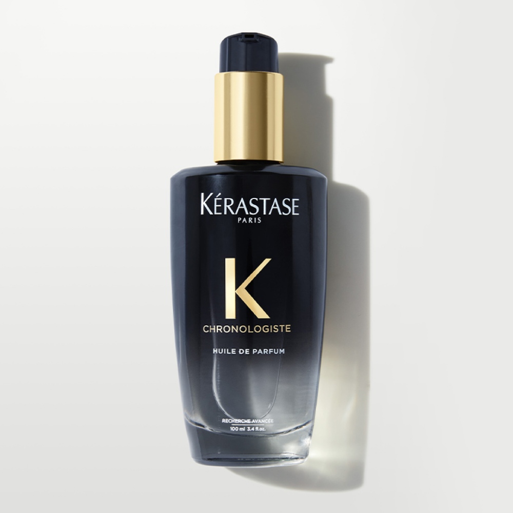 O óleo capilar Chronologiste Huile de Parfum é exibido em um fundo cinza puro. O óleo apresenta uma mistura artística de fragrâncias cativantes, proporcionando brilho e nutrição aos cabelos.